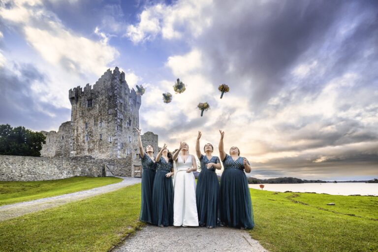 Bride and bridesmaids throwing their flowers in the air at Ross Castle Killarney Co Kerry