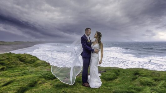 Bride and groom holding hands on the beach in the soft rain at Blair Cove, Cork, JOD'Photography