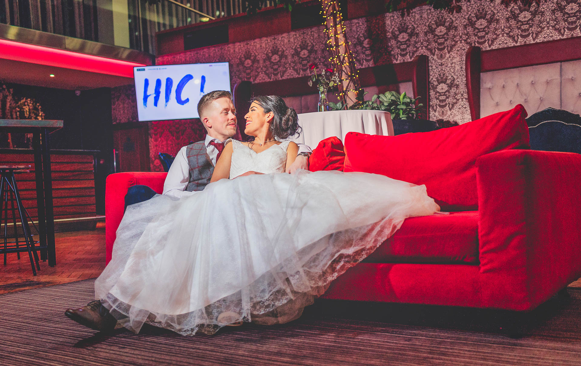 Bride and groom take a quiet moment to relax on the red couch in Rochestown park hotel Cork