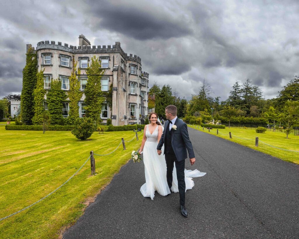 Bride and groom walking away from Ballyseede castle Tralee as the dramatic sky looks like it wants to crush them