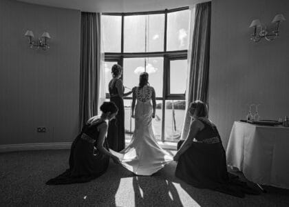 bridesmaids fixing bride by the window light at Celtic Ross Hotel Cork
