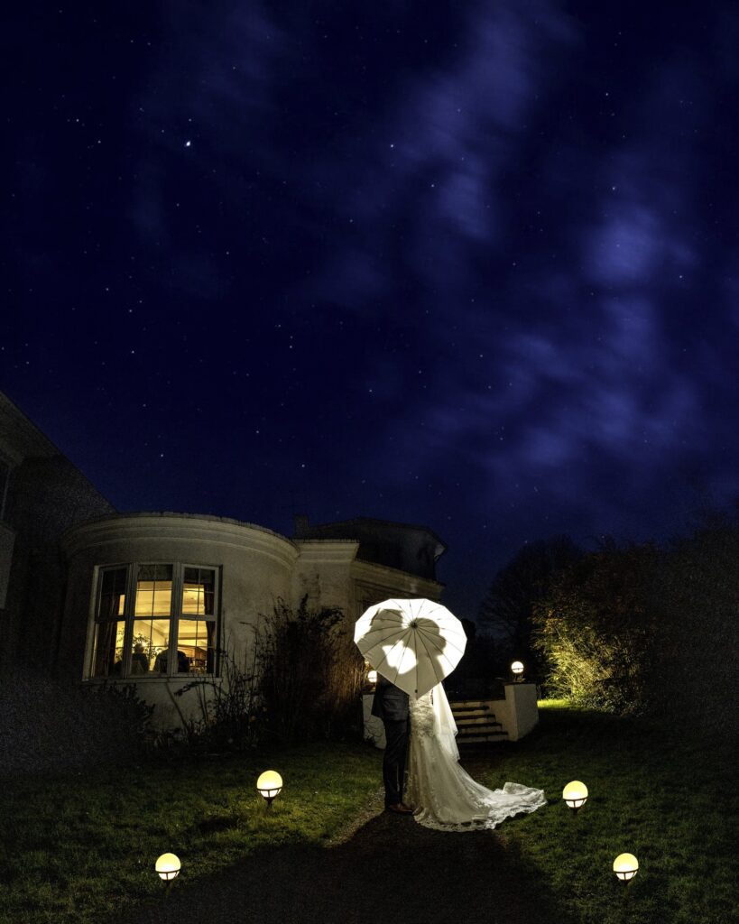 Creative portrait of bride and groom holding an umbrella while i light them from behind using a Godox flash to cast their silhouettes onto the umbrella at a Cork wedding venue