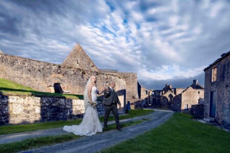 Bride and groom standing on rugged coastal cliffs at sunset – JOD Photography