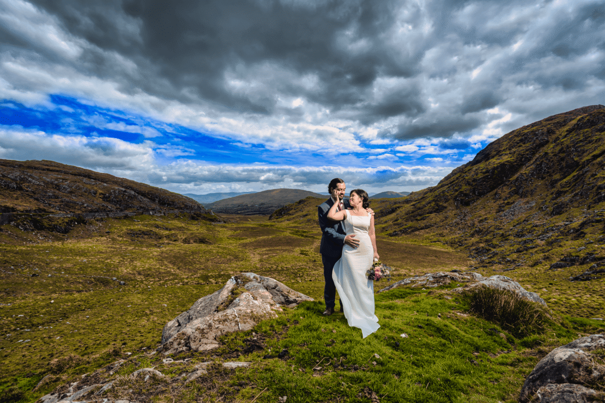 Couple embracing outdoors with dramatic Irish landscape backdrop