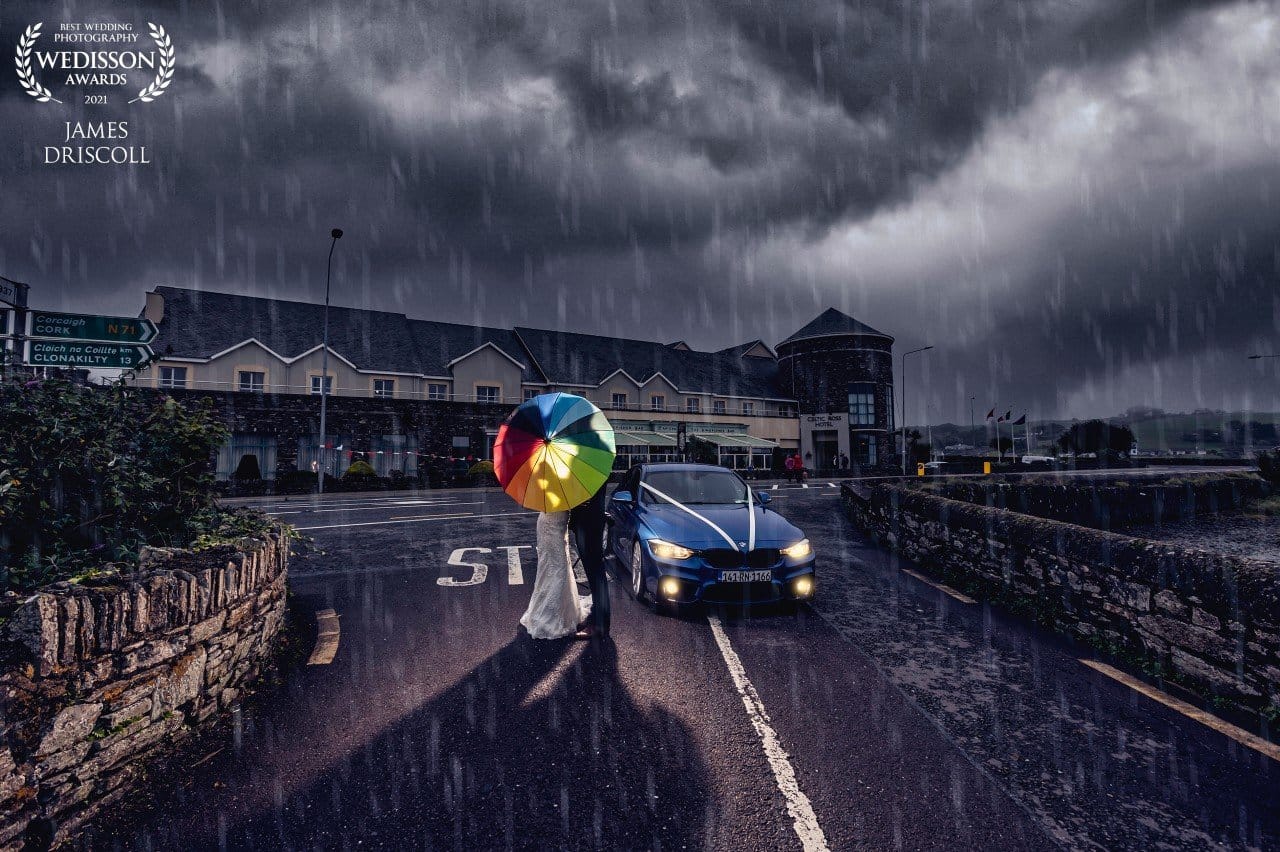 Night time portrait of bride and groom sharing a romantic kiss under an umbrella as the Irish weather turns to rain