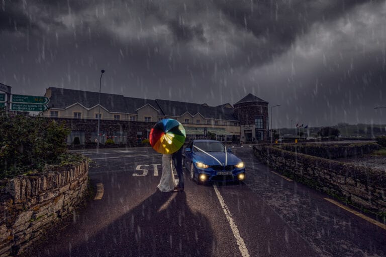 Stormy evening wedding portrait on a wet road with a car and colourful balloons