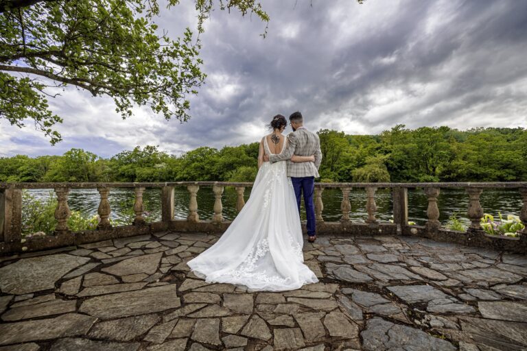 Bride and groom on a stone terrace overlooking trees and a lake in Killarney, Co. Kerry