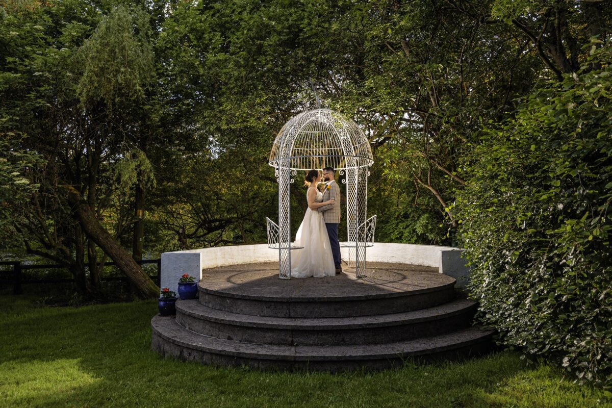 Vibrant gardens at Innishannon House Hotel bloom under a summer sky, framing a joyful wedding scene, shot by JOD'Photography.