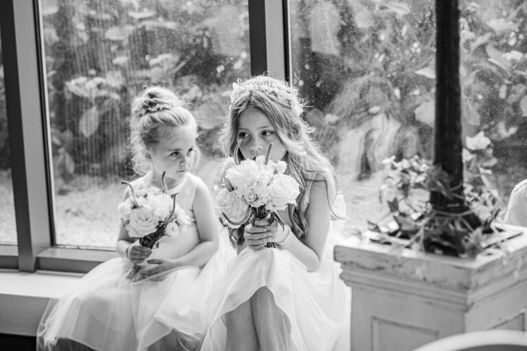 Two young flower girls smiling together at a wedding