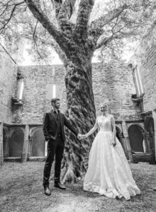 Paul smiling as he looks at Holly under the trees – JOD'Photography
