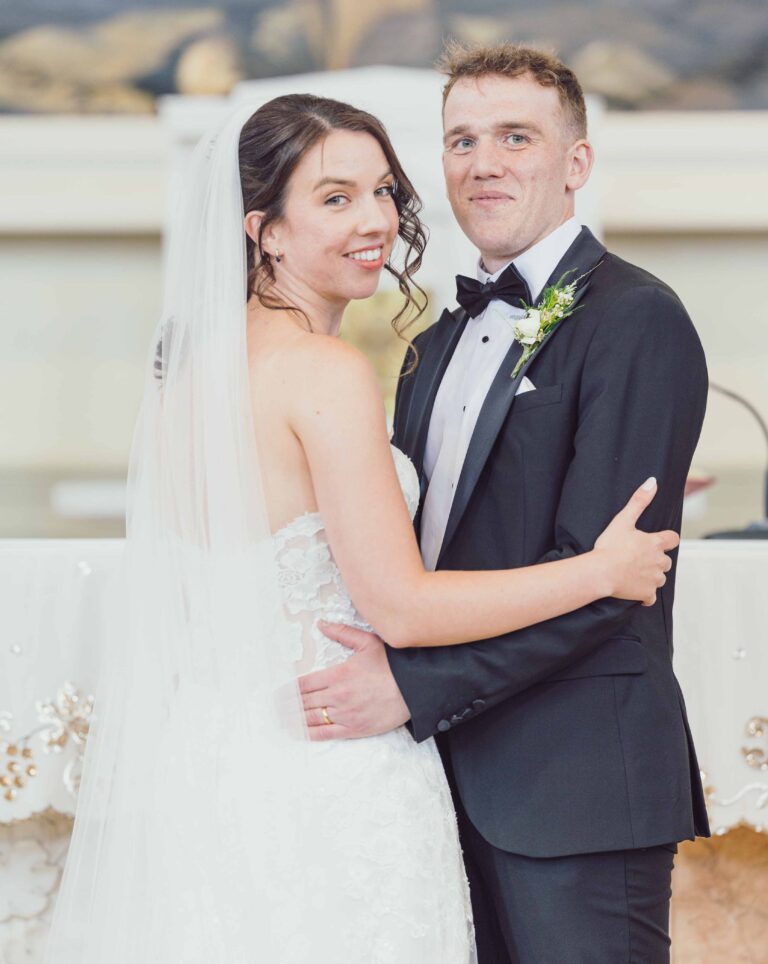 Bride and groom embracing and smiling at the camera at their Kinsale wedding, Co. Cork