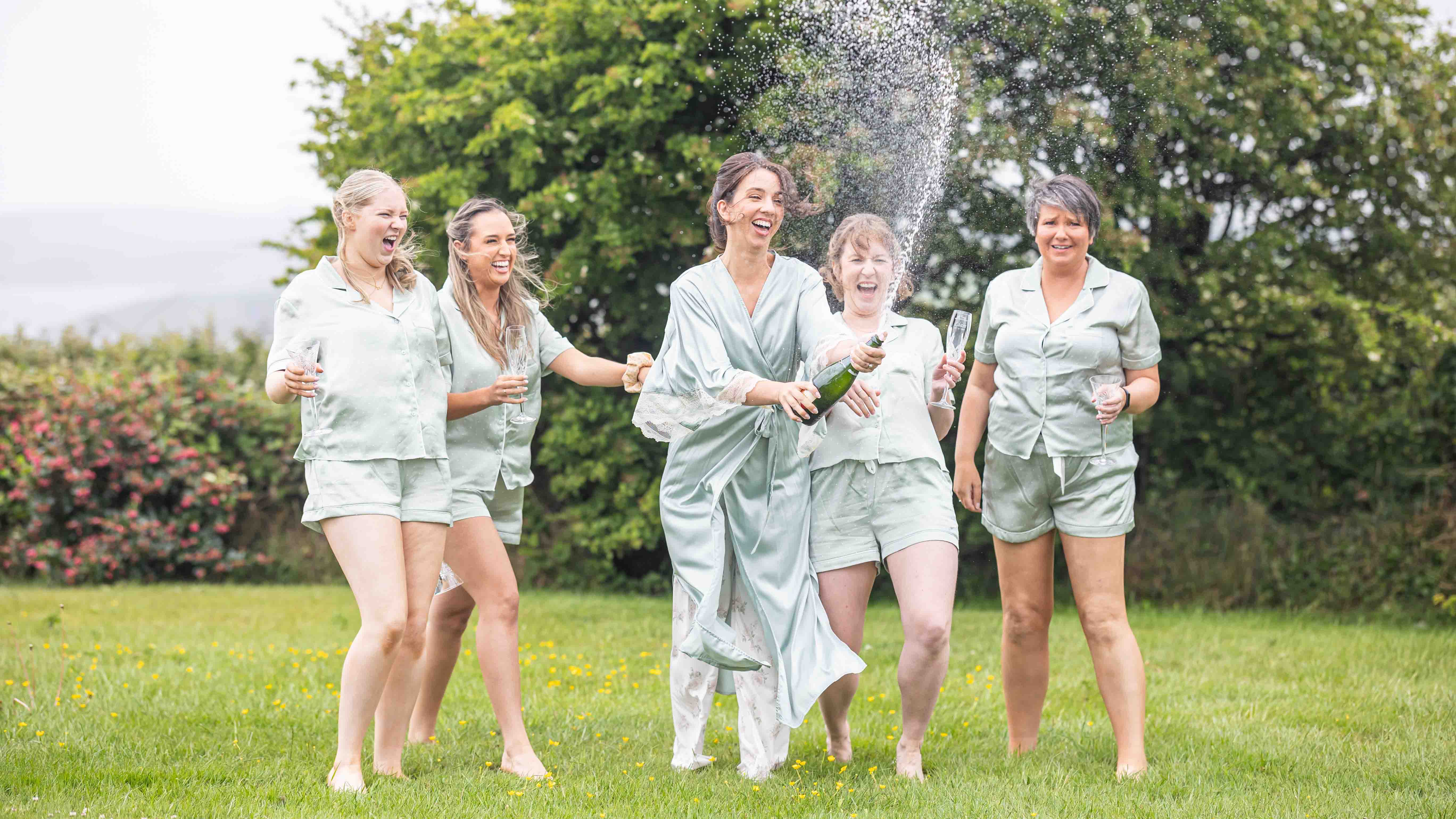 Bridesmaids laughing during champagne spray – JOD'Photography