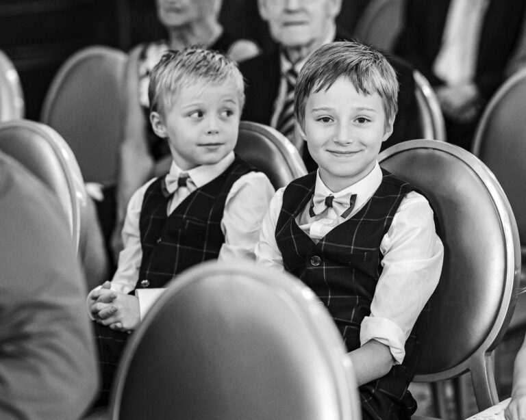 Two little boys in waistcoats smiling from their chairs during the ceremony at The Brehon, Killarney