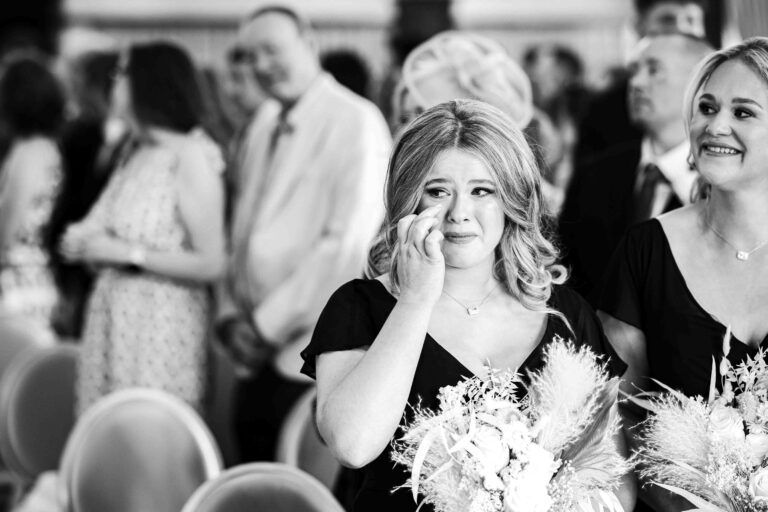 Black and white photo of a guest wiping away a tear during the wedding ceremony at The Brehon, Killarney