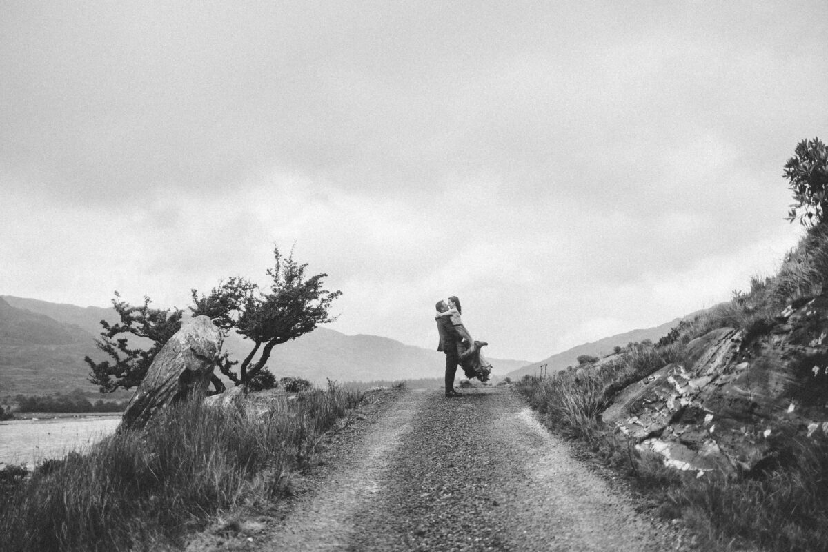 Black and white photo of a couple kissing on a mountain road in the Gap of Dunloe, Co. Kerry