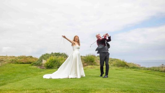 Bride smiling in coastal wind during wedding photos
