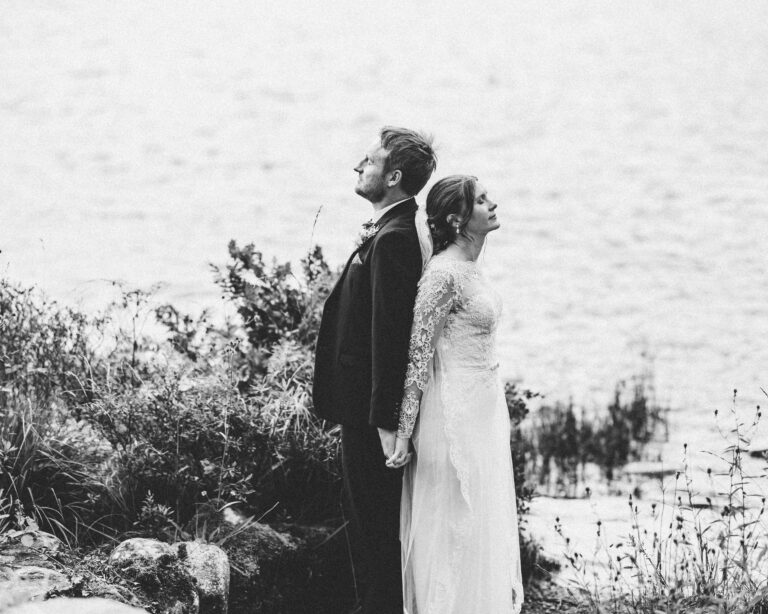 Black and white photo of a bride and groom holding hands by the lake at Gougane Barra, West Cork
