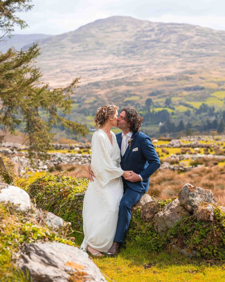 Bride and groom kissing with a mountain view behind, Co. Kerry