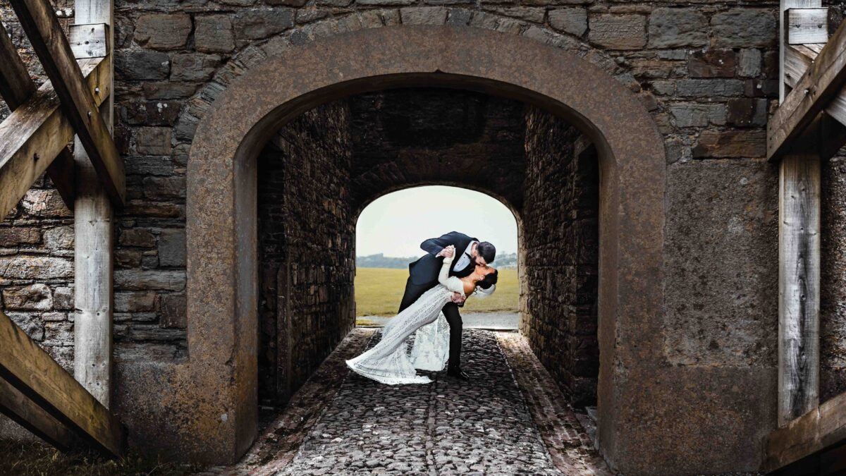 Bride and groom walking through stone archway — Charles Fort wedding photos — JOD Photography