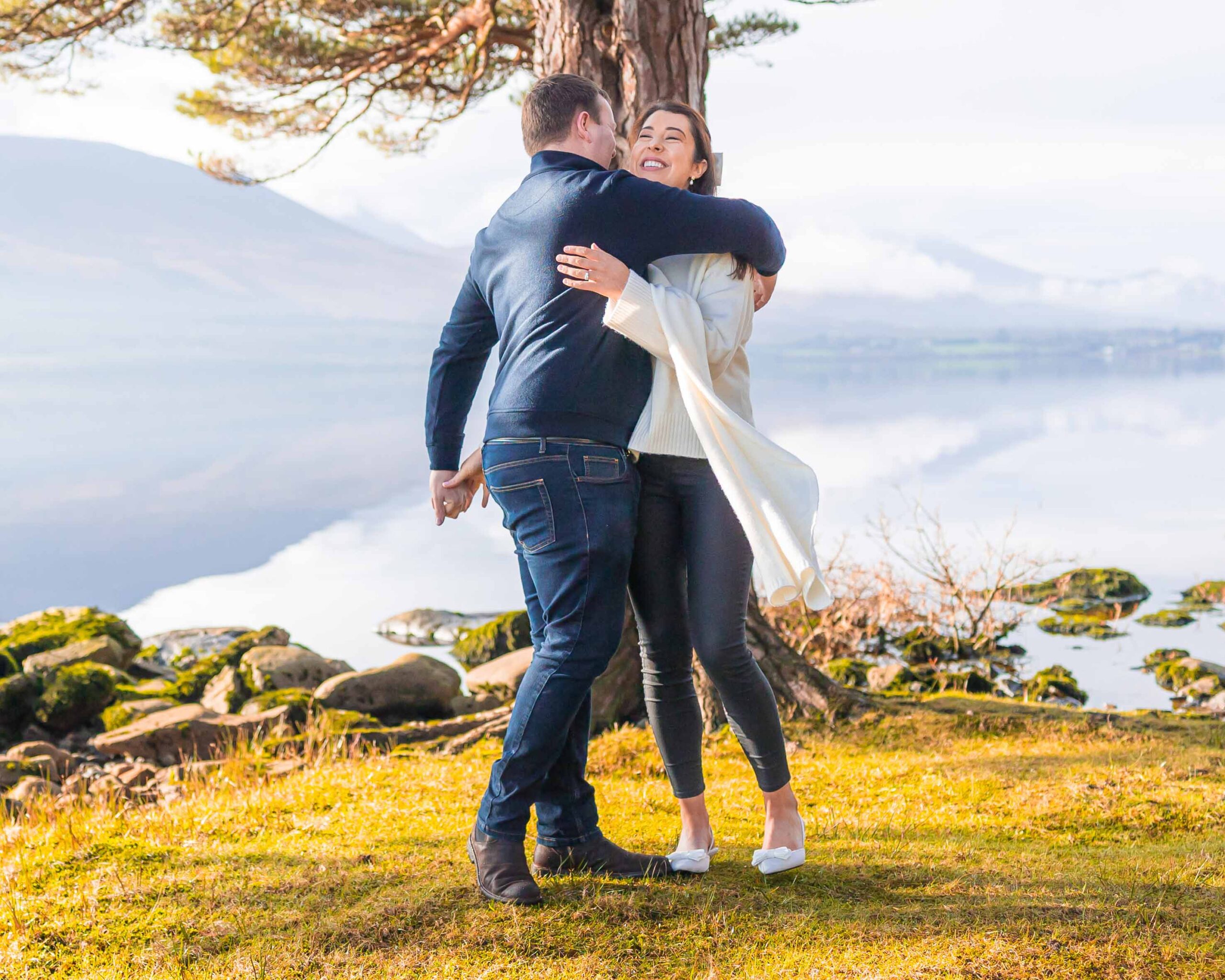 Happy couple hugging beside the lake during their Killarney engagement shoot — JOD Photography