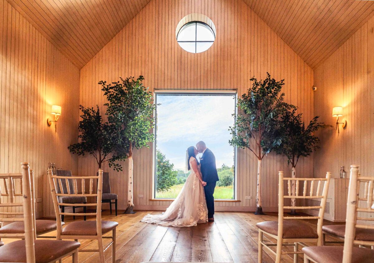Bride and groom kissing in the open doorway of a timber wedding chapel
