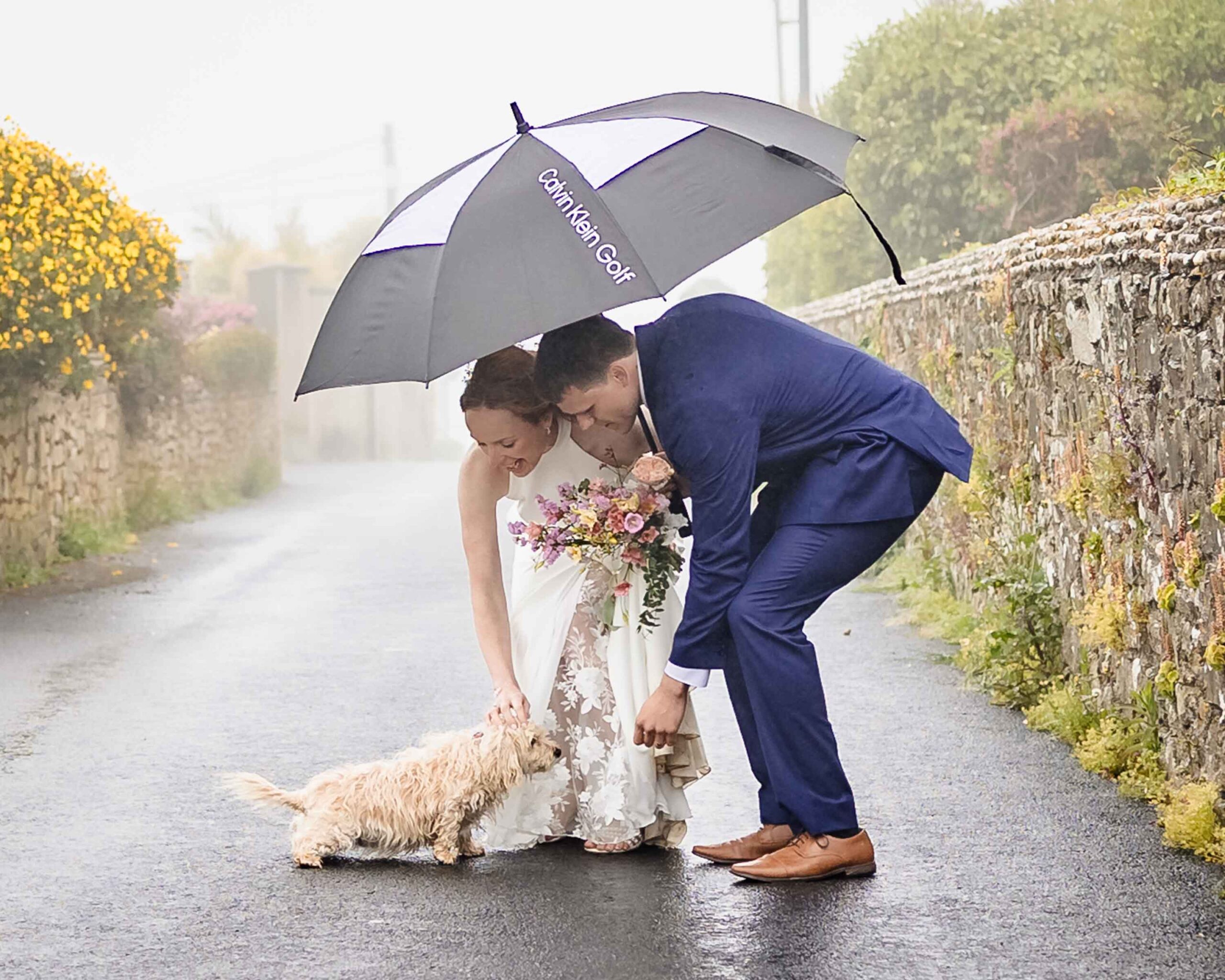 Bride and groom beside Tramore coastline in rain