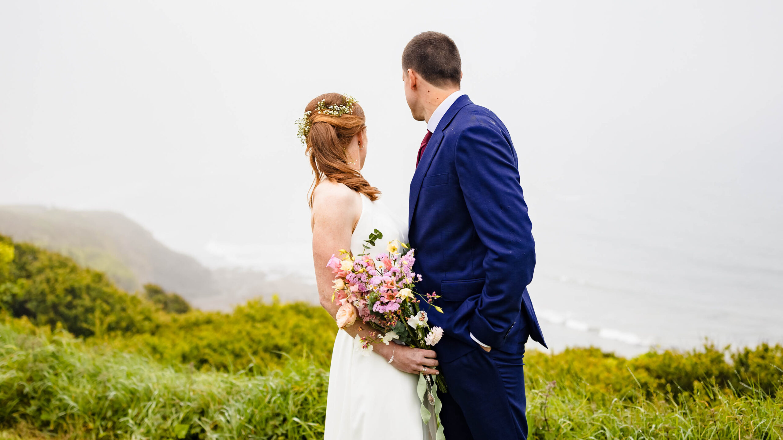 Bride and groom laughing in rain at Tramore cliffs