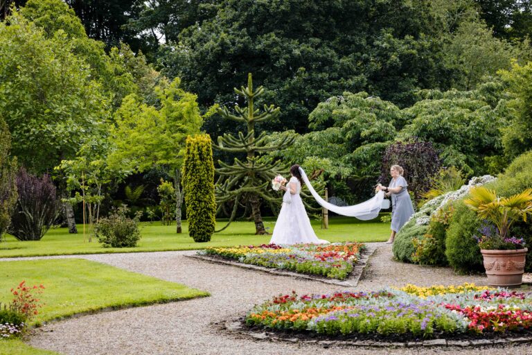 Bride with a long veil walking through the formal gardens at Vandeleur Walled Garden, Co. Clare
