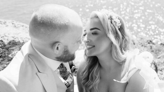 Close-up romantic wedding portrait of a bride and groom embracing on a sunny beach at Long Strand, West Cork