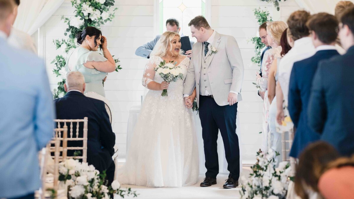 Bride and groom laughing together as they walk down the aisle