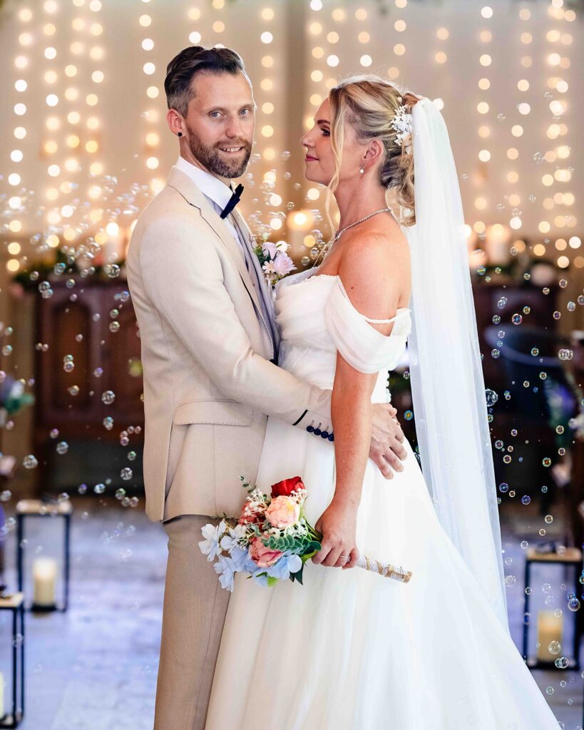 Bride and groom sharing a laugh as bubbles are blown during their ceremony