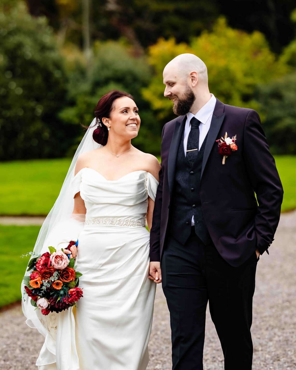 Bride and groom walking hand in hand and smiling at each other in the grounds of Fota House, Cork