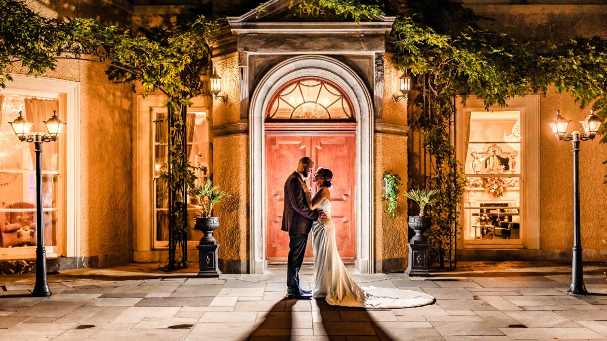 Sinéad and Dave kissing in the glowing arched doorway at night under lantern light, Vienna Woods Hotel wedding, Cork