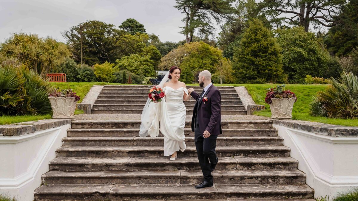Bride and groom walking down the stone steps through the formal gardens at Fota House and Gardens, Cork
