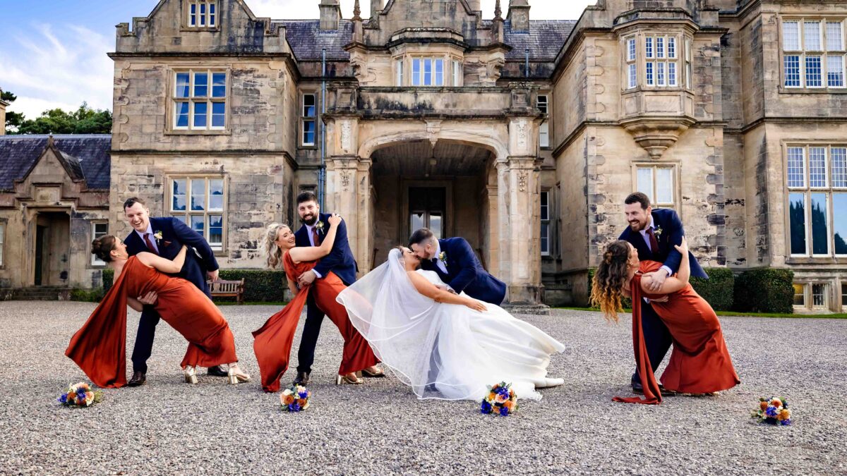 Wedding party dip photo at Muckross House, Killarney: bridesmaids and groomsmen dipping their partners beside the bride and groom