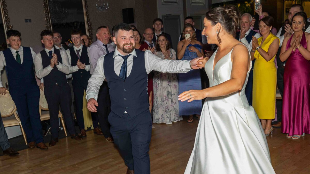 Bride and groom dancing together as guests clap and watch at their wedding reception at The Oaks Hotel, Killarney