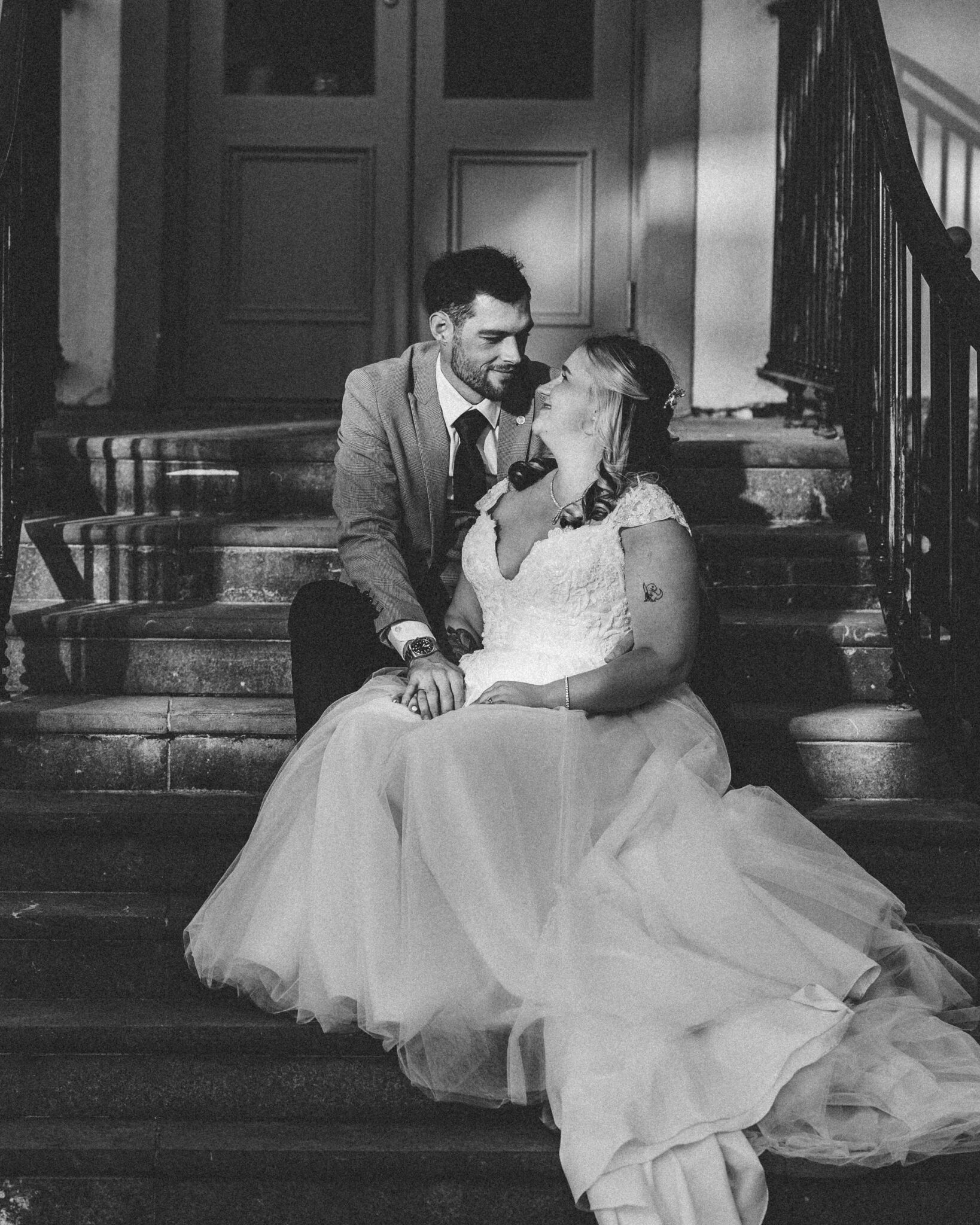 Black and white photo of Shannon and Brandon laughing together on the steps of the Talbot Hotel Cork