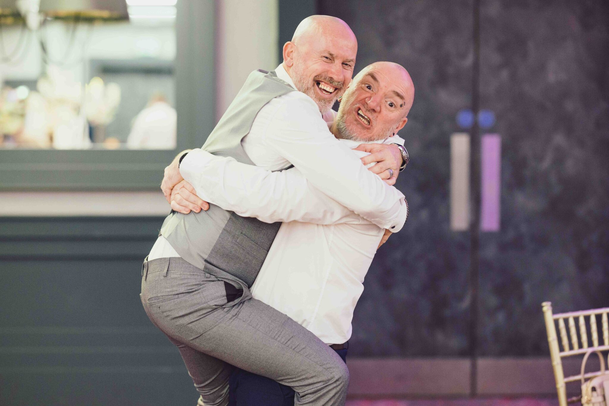 Two men share a big laughing hug outside the Talbot Hotel Cork wedding, family fun, Cork wedding photographer