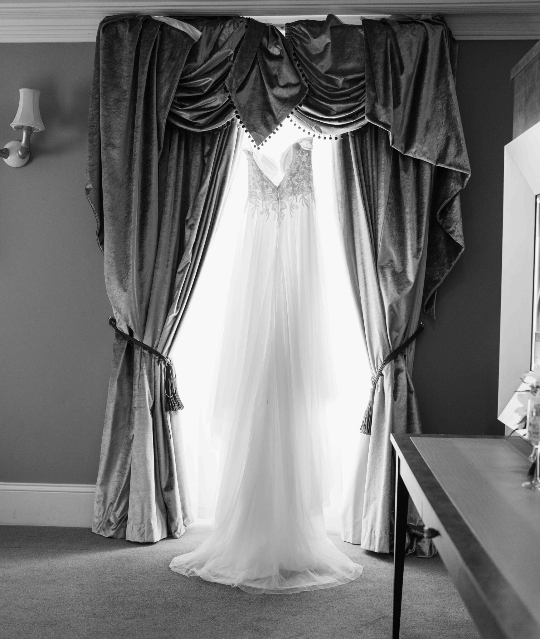 Black and white photo of Shannon's wedding dress hanging by velvet curtains at the Talbot Hotel Cork wedding
