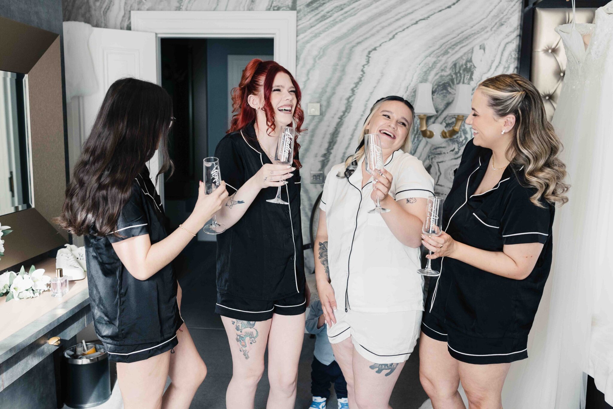 Shannon's bridesmaids in black pyjamas laugh and toast with champagne in the bridal suite at the Talbot Hotel Cork