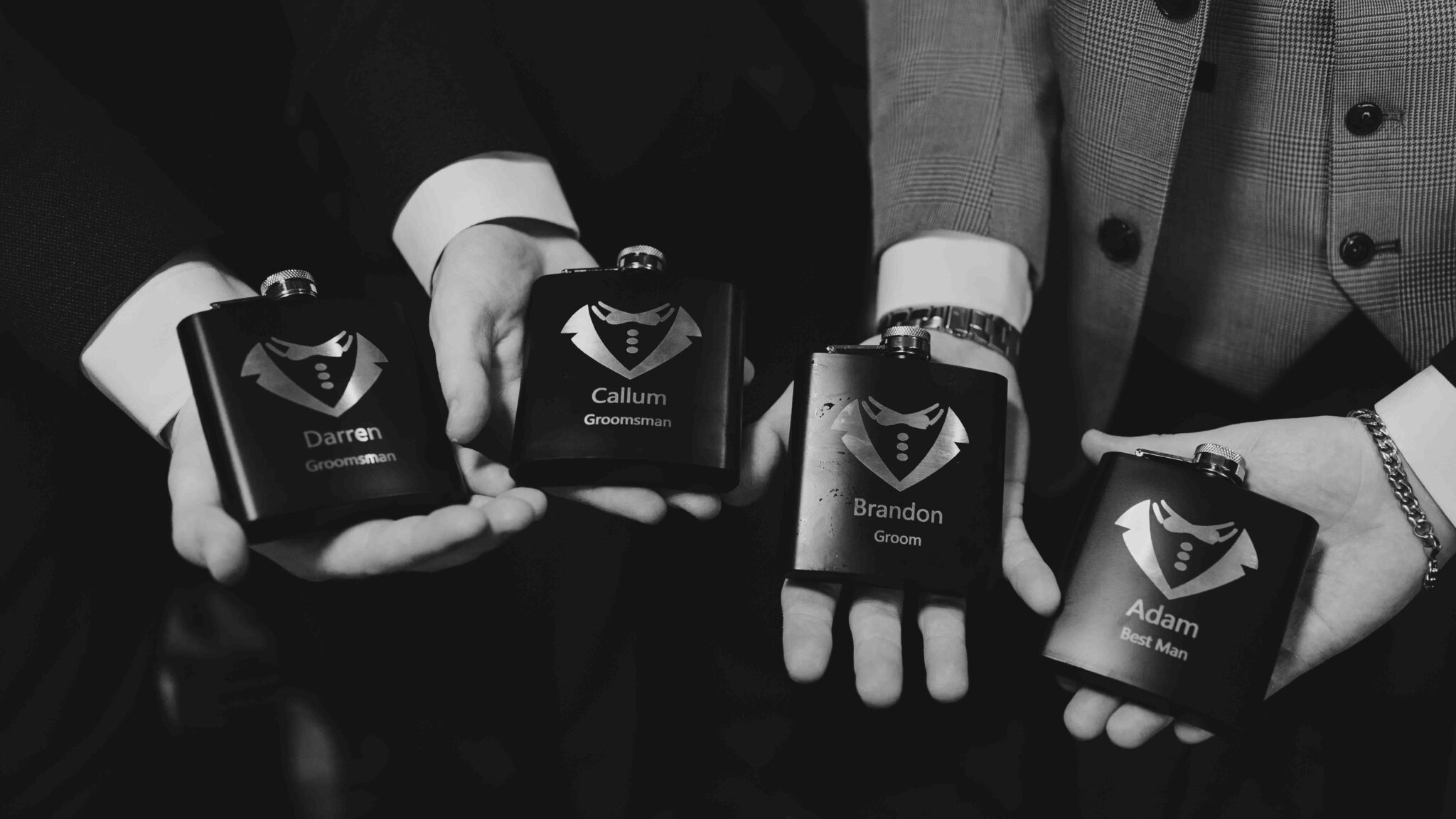 Black and white photo of four hip flasks held by the groomsmen before the Talbot Hotel Cork wedding