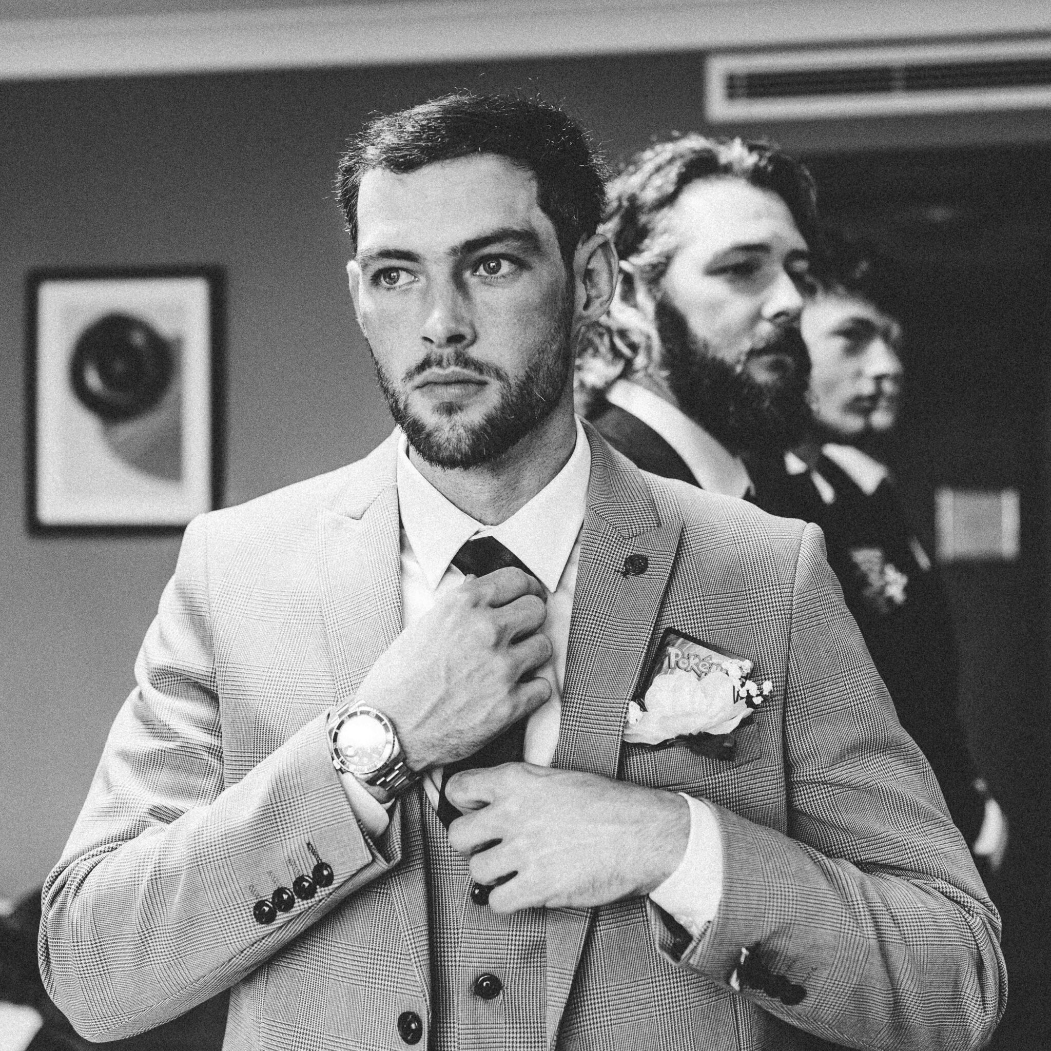 Black and white photo of Brandon adjusting his tie with his brothers behind him at the Talbot Hotel Cork