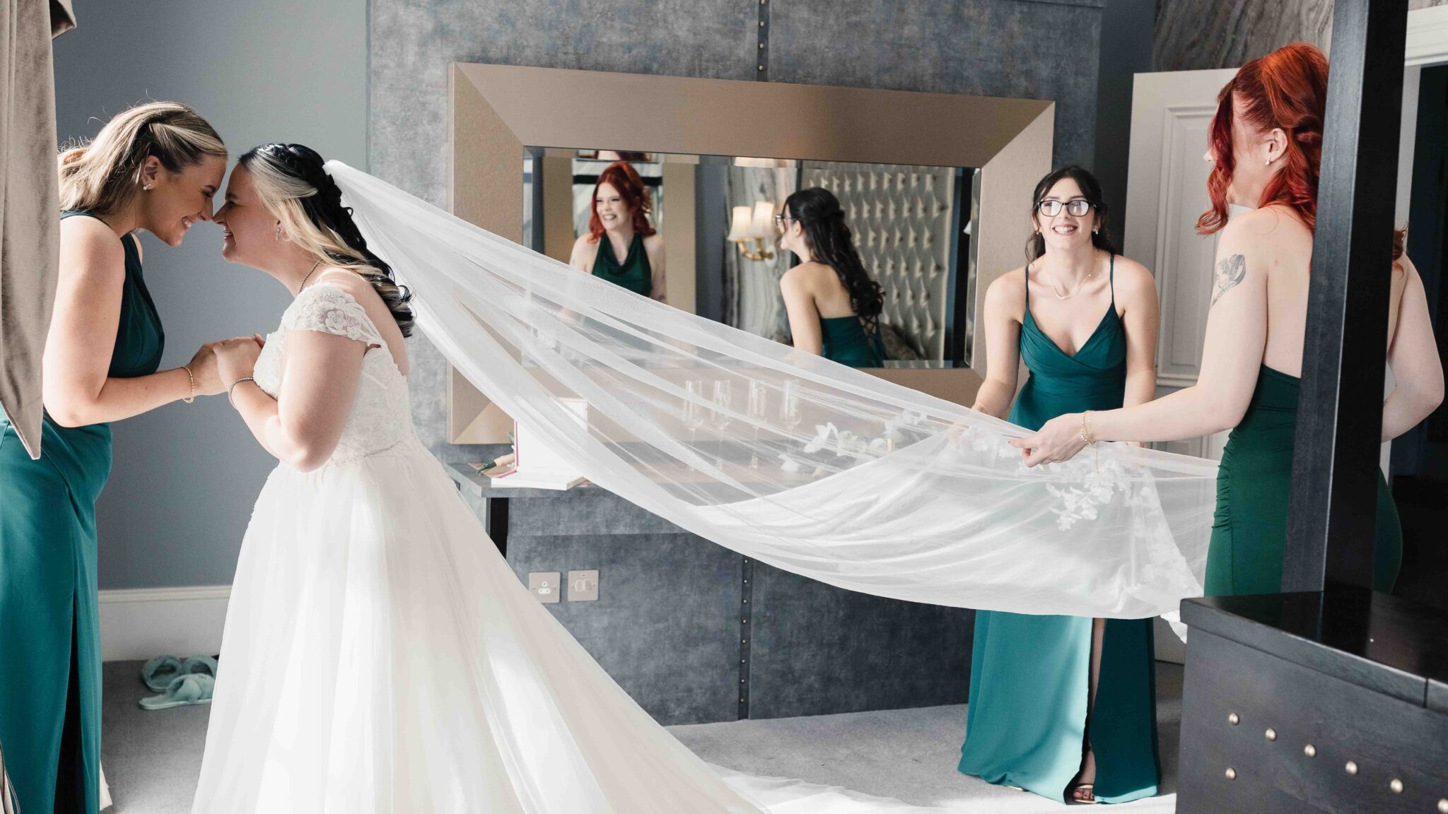 Bridesmaids lift Shannon's long veil in front of the mirror at the Talbot Hotel Cork on the morning of the wedding
