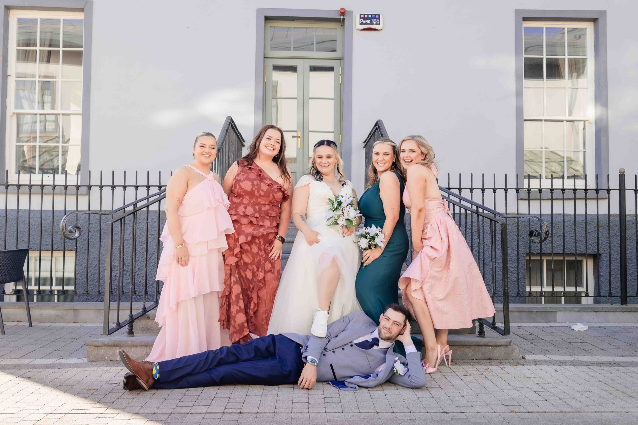 The bridal party pose outside the Talbot Hotel Cork while Brandon lies on the ground, relaxed wedding photography