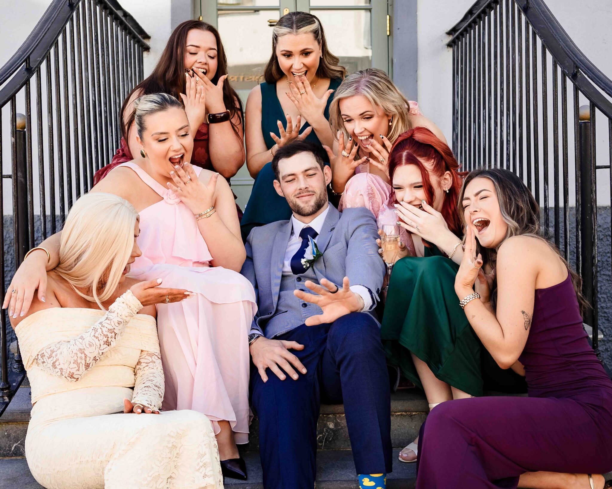 Brandon sits on the hotel steps surrounded by laughing friends at the Talbot Hotel Cork wedding, relaxed wedding photographer Cork