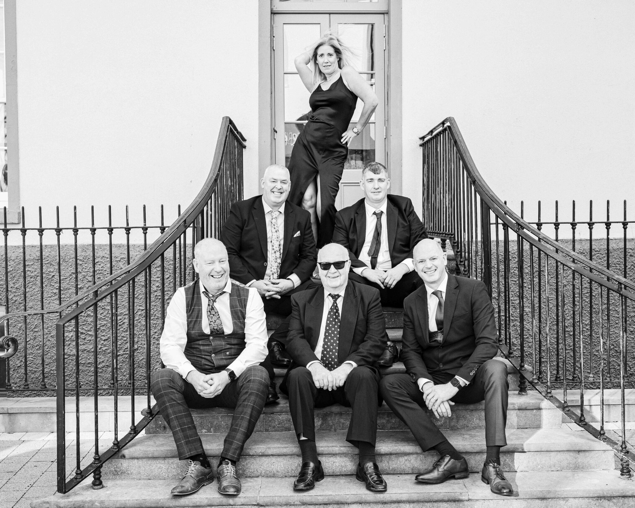 Black and white photo of the groom's family sitting on the steps at the Talbot Hotel Cork wedding