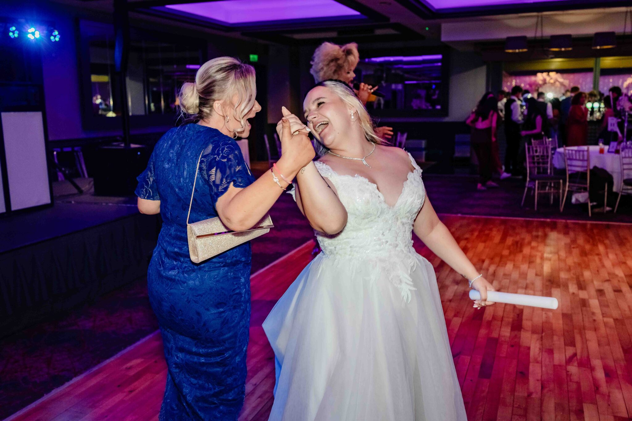 Shannon laughs and dances with a guest in a blue lace dress at the Talbot Hotel Cork wedding reception