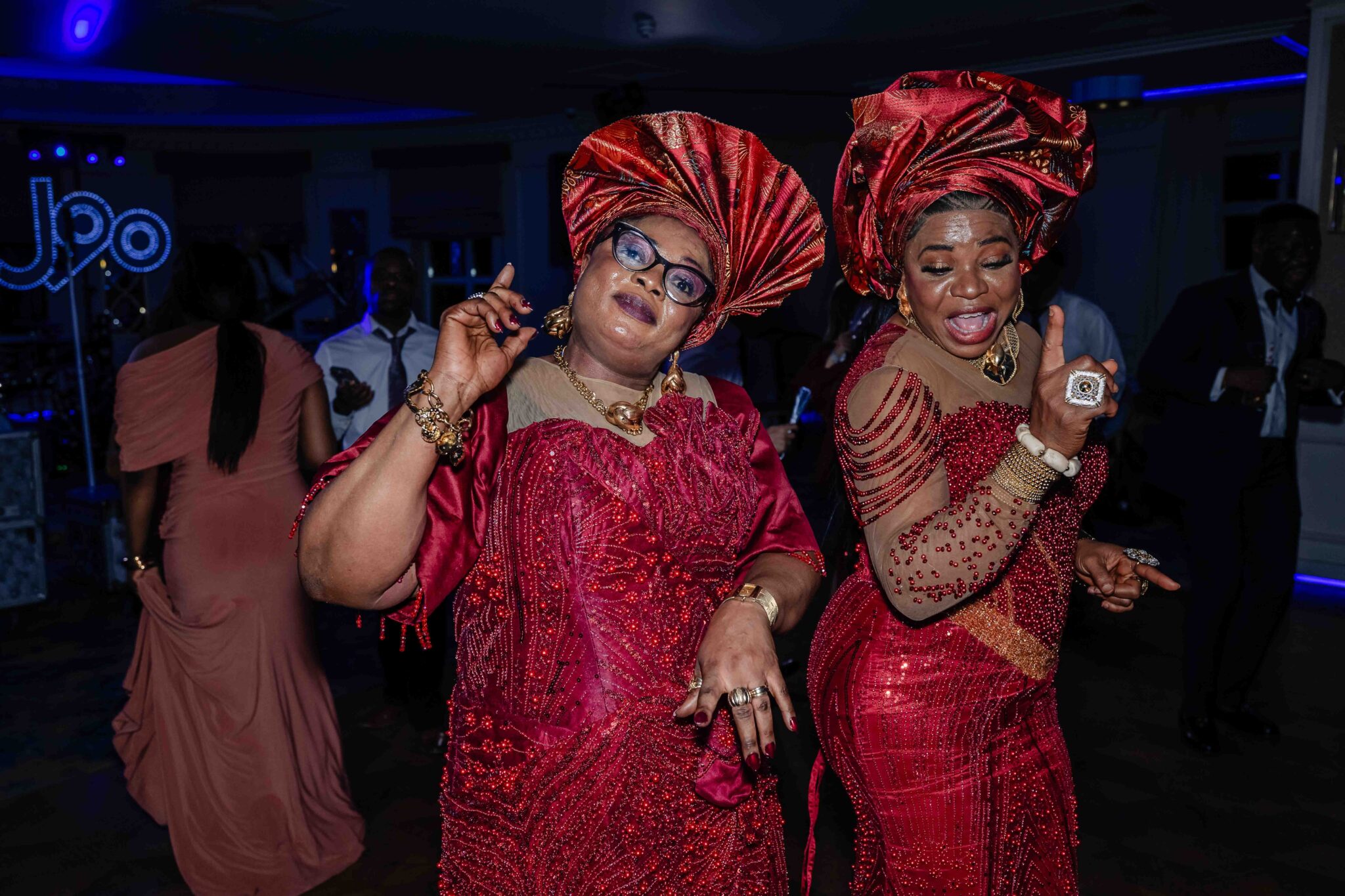 Two guests in red gele headwraps dance at the Irish Nigerian wedding at Vienna Woods Hotel, Cork