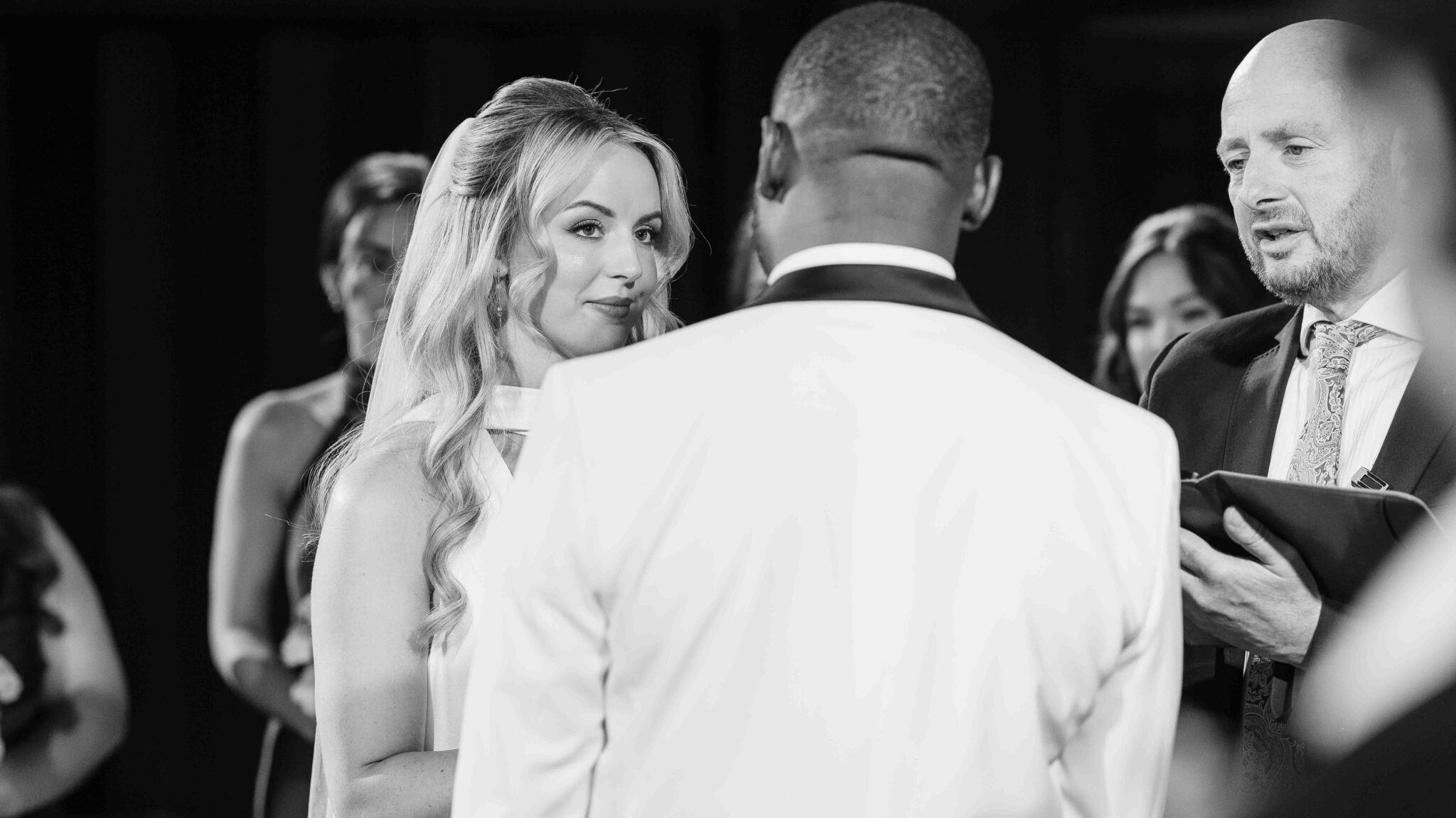 Black and white photo of bride and groom with the pastor during their wedding ceremony at Cork Church, Cork