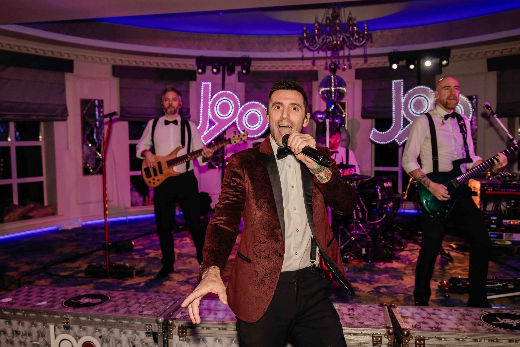 J90 wedding band singer in a red velvet jacket performs on stage at Vienna Woods Hotel, Cork wedding band